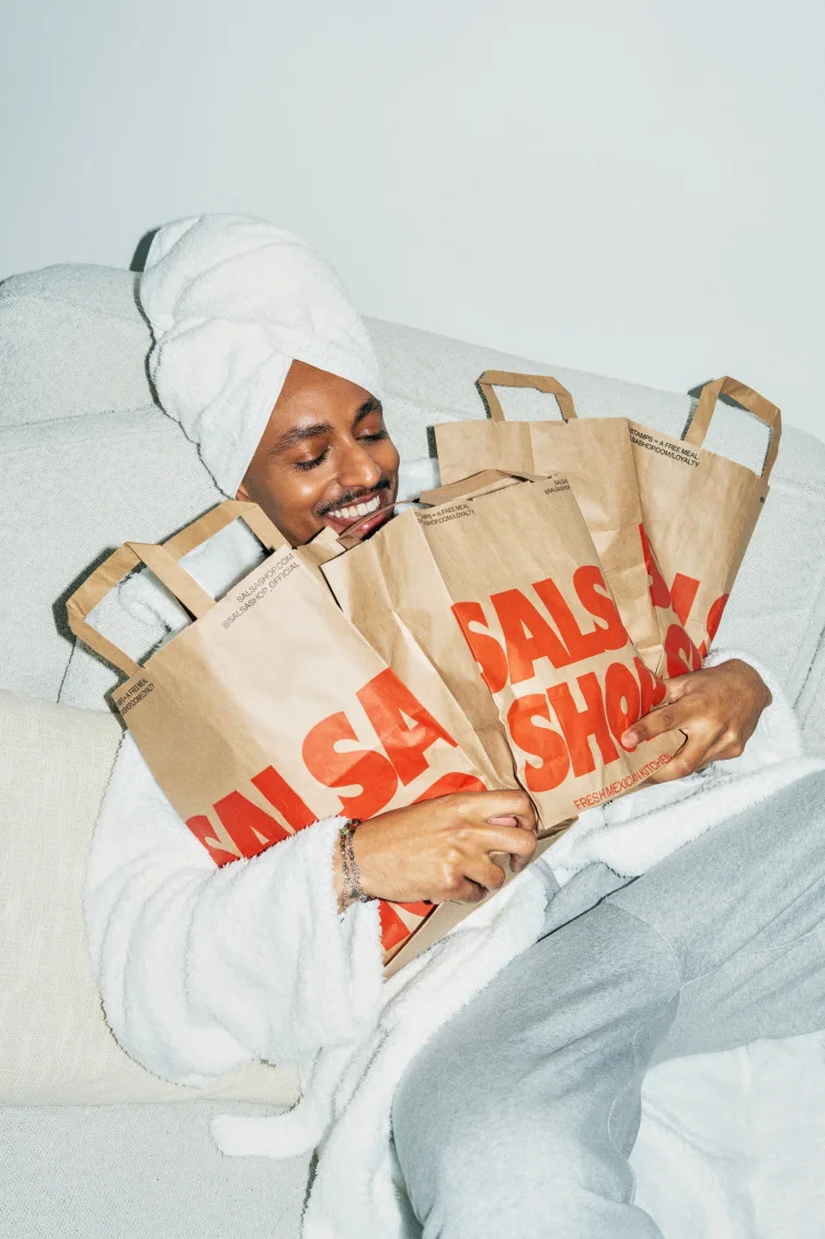 A happy guest wrapped in a robe hugging an armful of Salsa Shop takeaway bags