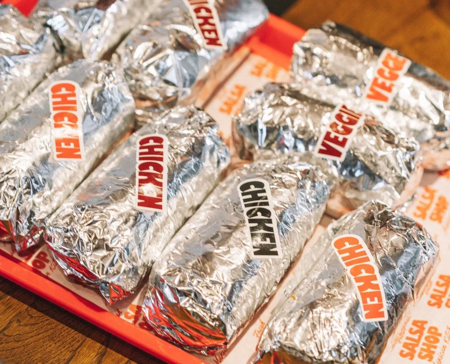 Salsa Shop Chicken burritos wrapped in foil on a platter.