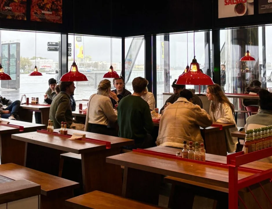 Focus group participants eating inside the Salsa Shop location at Amsterdam Central Station, testing menu items and giving real-time feedback as part of customer research.