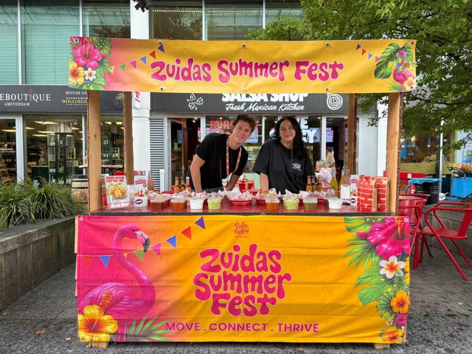 Salsa Shop team serving a selection of salsas from a colourful stall at Zuidas Summer Fest on Zuidplein in Amsterdam.